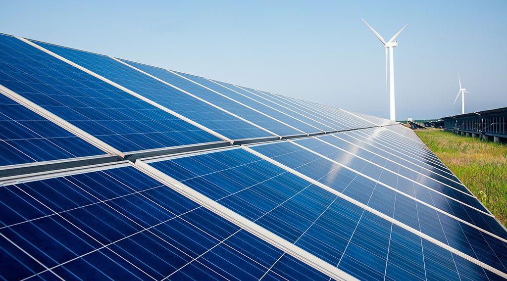 A wind turbine behind solar panel